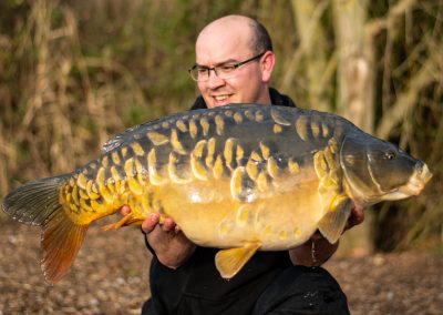 Angler holding a mirror carp at Scarlett’s Lake