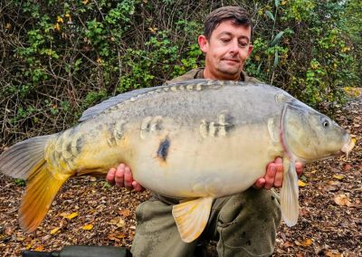 Angler holding a large mirror carp at Scarlett’s Lake